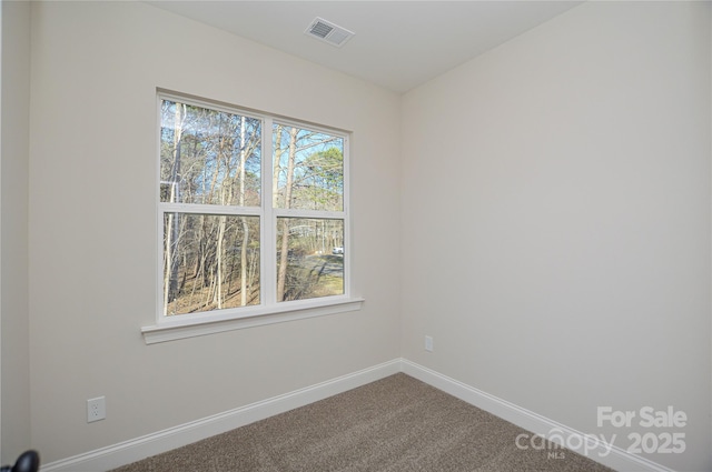 unfurnished room featuring baseboards, visible vents, and dark carpet