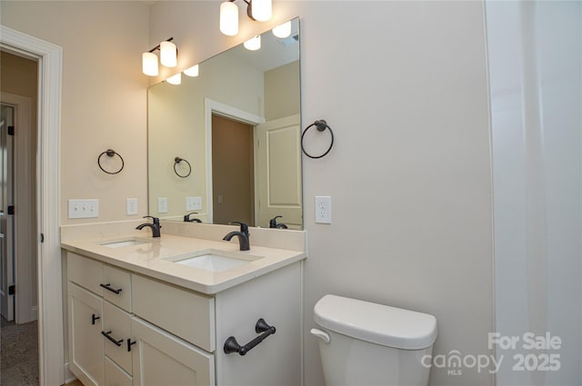bathroom with toilet, double vanity, and a sink