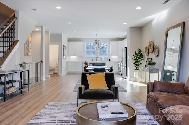 living room featuring sink, a chandelier, and light hardwood / wood-style flooring