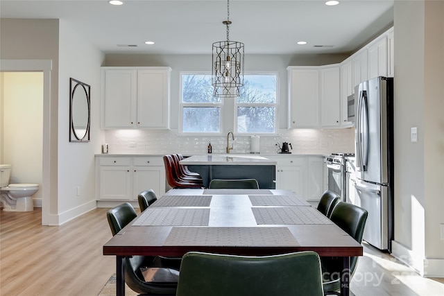 kitchen with decorative light fixtures, stainless steel appliances, decorative backsplash, and white cabinets