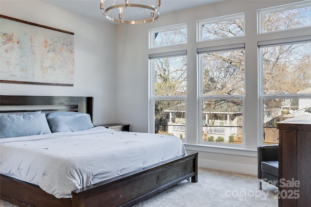 bedroom featuring light carpet, multiple windows, and a chandelier