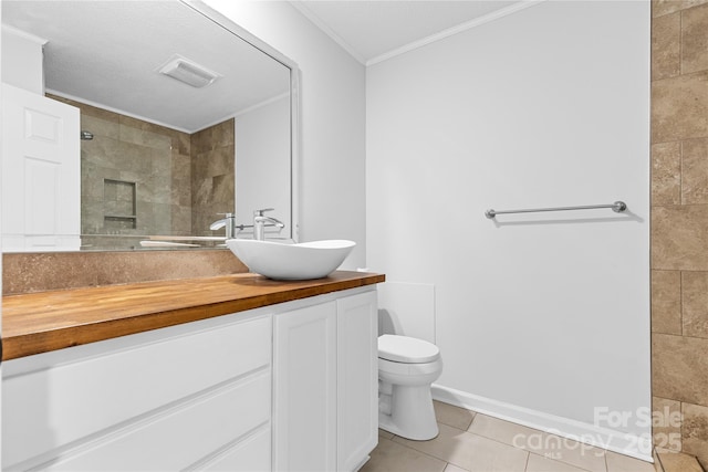 bathroom with crown molding, tiled shower, tile patterned floors, and toilet