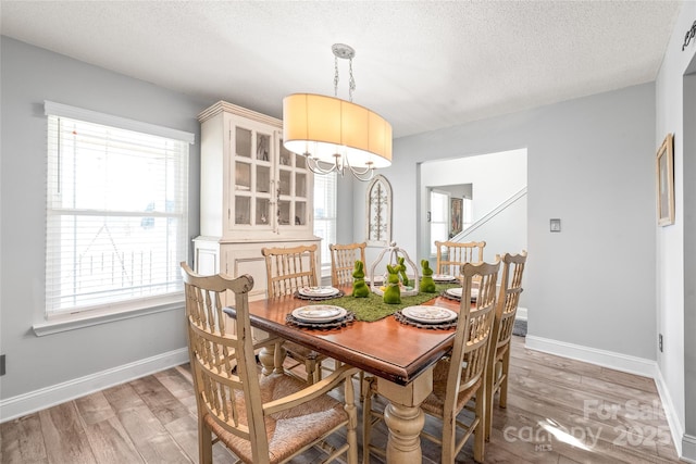 dining room featuring a textured ceiling, baseboards, and wood finished floors