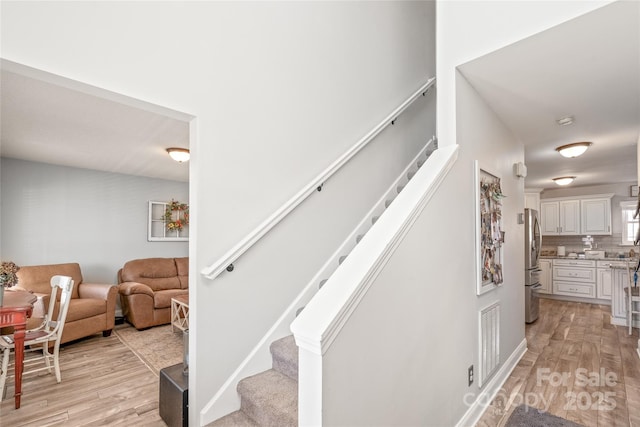 staircase with visible vents and wood finished floors