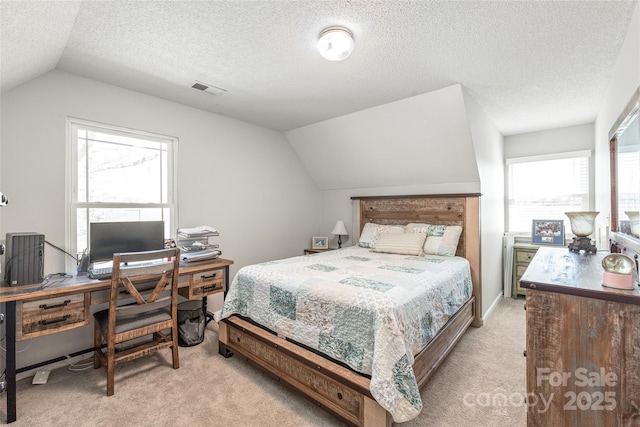 bedroom with vaulted ceiling, a textured ceiling, visible vents, and light colored carpet