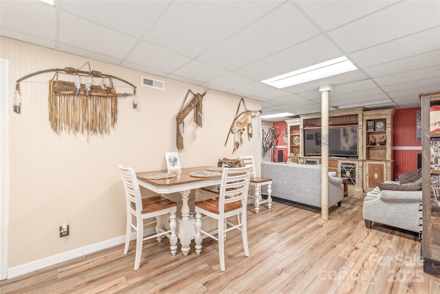 dining space with baseboards, visible vents, a drop ceiling, and wood finished floors