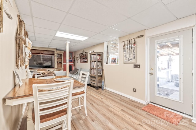 dining space with a drop ceiling, baseboards, and wood finished floors