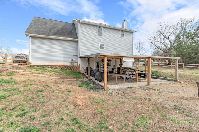 back of property with a patio area, a chimney, and fence