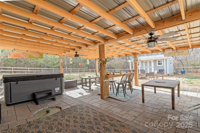 view of patio / terrace with a hot tub, a fenced backyard, and an outdoor structure