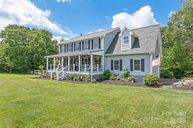 rear view of property featuring covered porch, aphalt driveway, a shingled roof, and a lawn