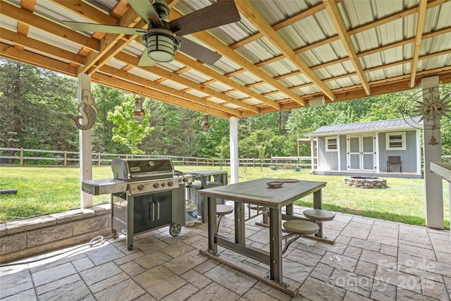 view of patio featuring a fire pit, outdoor dining space, a fenced backyard, and an outdoor structure