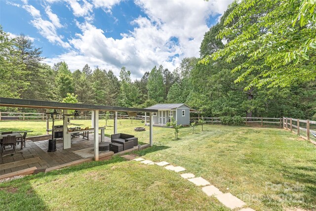 view of yard featuring an outdoor structure, an outdoor hangout area, a patio area, a storage shed, and a fenced backyard