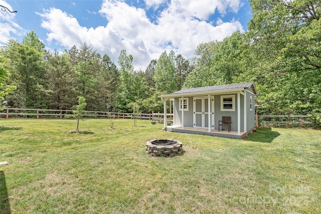 view of yard with an outbuilding, a fenced backyard, and an outdoor fire pit