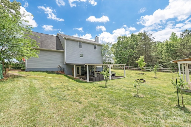 rear view of property featuring a lawn, a chimney, a patio, and a fenced backyard