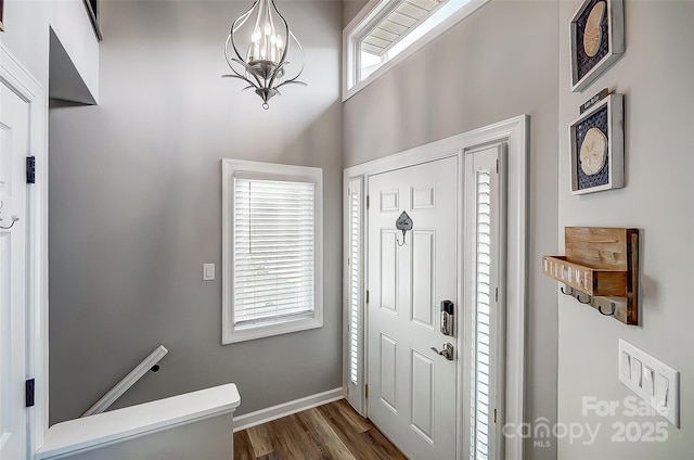 entryway featuring a towering ceiling, baseboards, and dark wood-type flooring