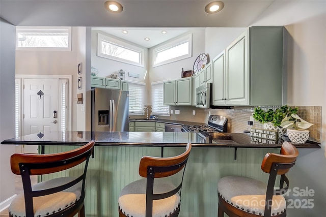 kitchen with appliances with stainless steel finishes, dark countertops, plenty of natural light, and backsplash