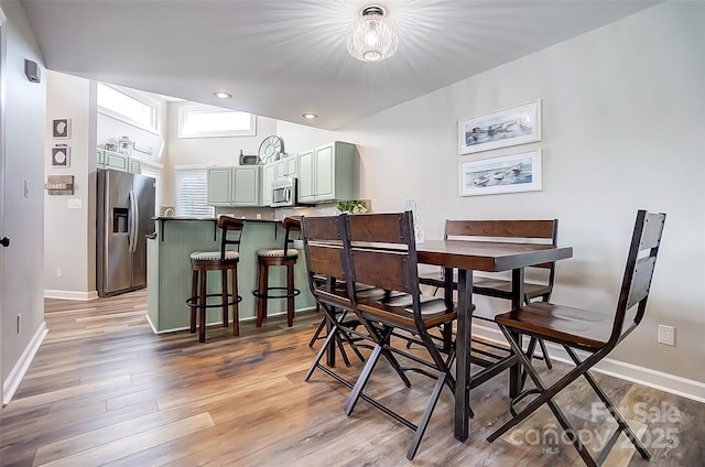 dining room featuring lofted ceiling, recessed lighting, light wood-type flooring, and baseboards