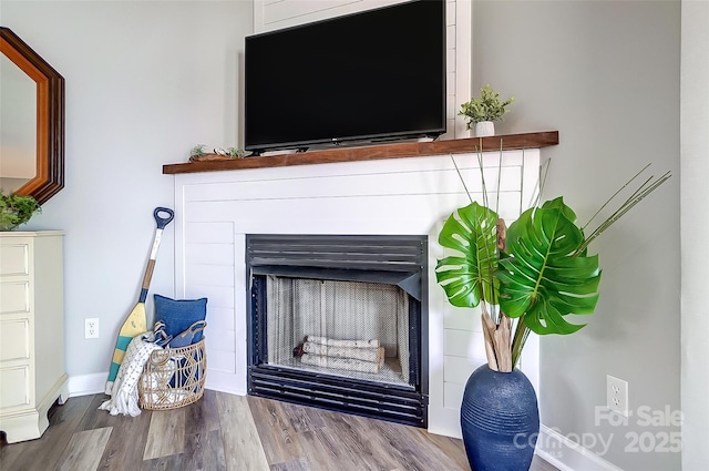 interior details with a fireplace, wood finished floors, and baseboards