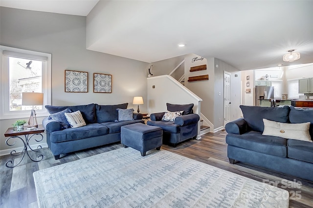 living area featuring baseboards, stairway, and wood finished floors