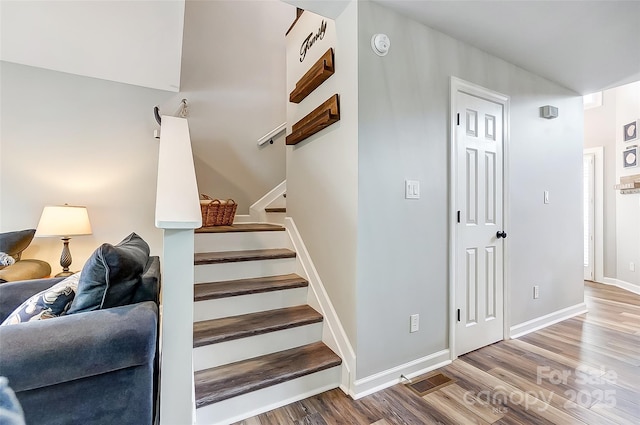 stairs with baseboards, visible vents, and wood finished floors