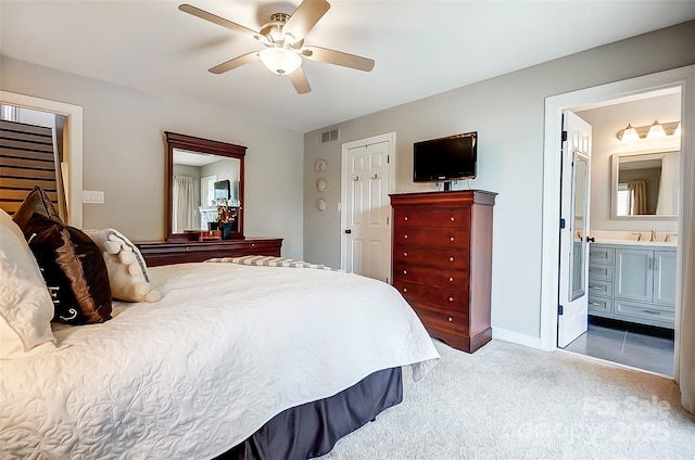 carpeted bedroom featuring visible vents, a ceiling fan, ensuite bathroom, a sink, and a closet