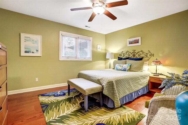 bedroom with a ceiling fan, wood finished floors, visible vents, and baseboards