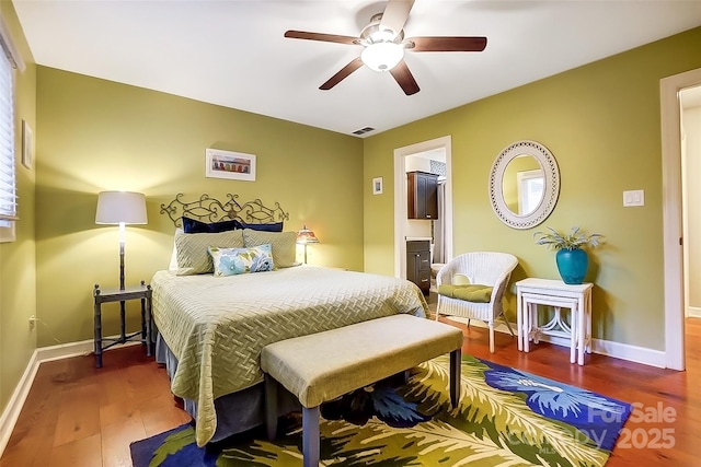 bedroom featuring ensuite bathroom, wood finished floors, a ceiling fan, visible vents, and baseboards