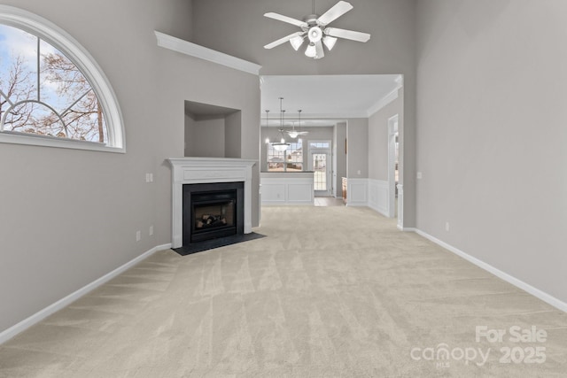 unfurnished living room featuring light colored carpet, ceiling fan with notable chandelier, and a towering ceiling