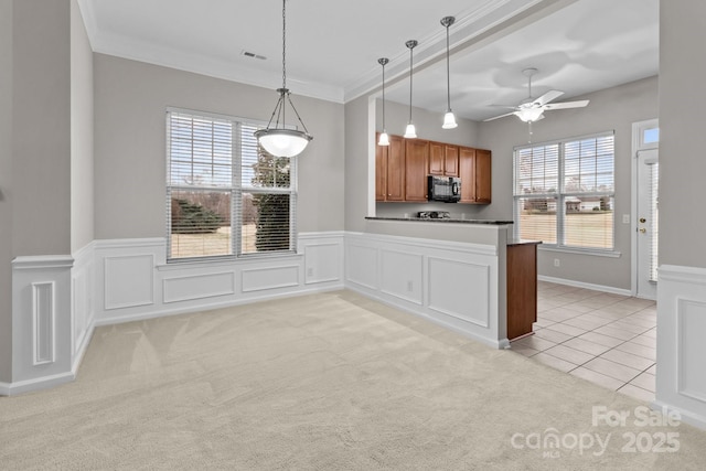 kitchen featuring light colored carpet, plenty of natural light, kitchen peninsula, and hanging light fixtures