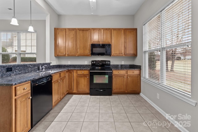 kitchen featuring sink, light tile patterned floors, dark stone countertops, hanging light fixtures, and black appliances