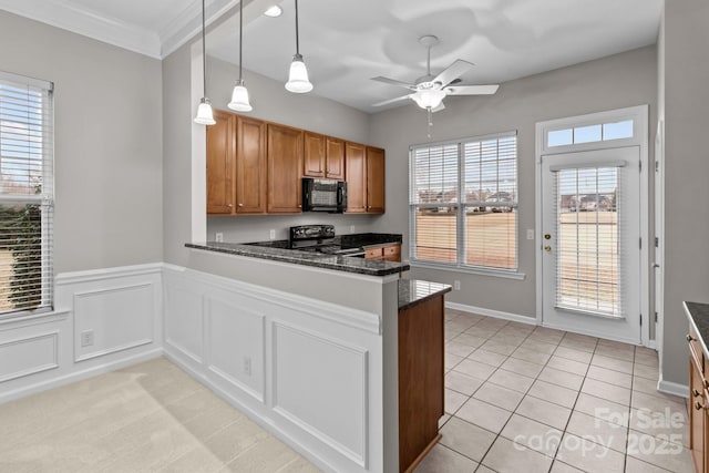 kitchen with pendant lighting, ceiling fan, black appliances, kitchen peninsula, and dark stone counters