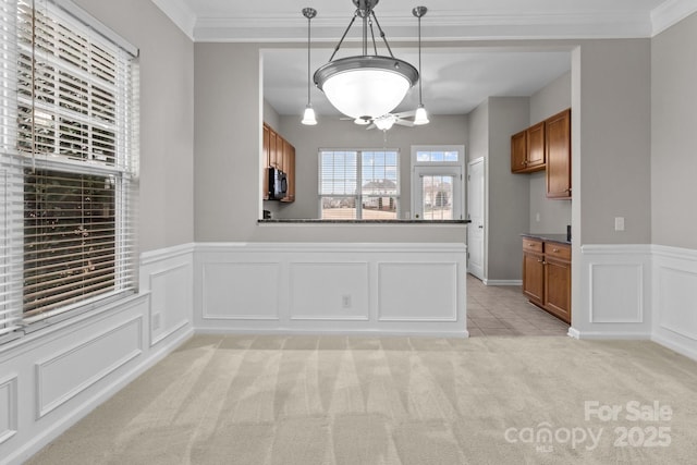 kitchen featuring hanging light fixtures, ornamental molding, light colored carpet, and kitchen peninsula