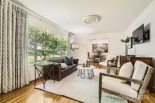 living area with baseboards, plenty of natural light, ornamental molding, and wood finished floors