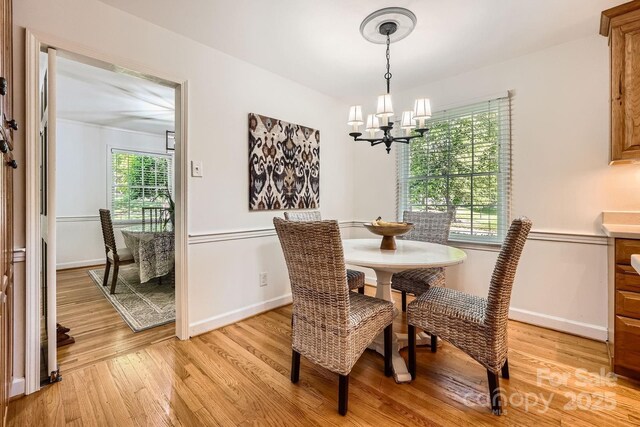 dining room featuring baseboards, a notable chandelier, and light wood-style flooring