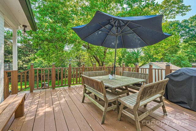 wooden deck with grilling area, an outbuilding, outdoor dining area, and a storage unit