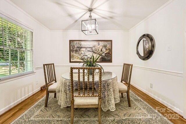 dining space featuring crown molding, wood finished floors, and a chandelier