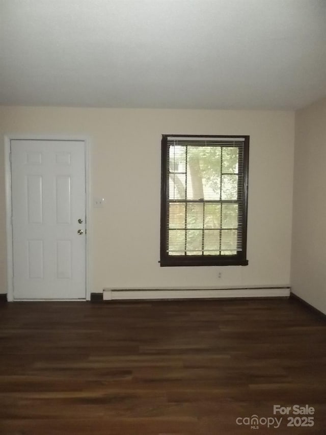 unfurnished room with a baseboard heating unit and dark hardwood / wood-style floors