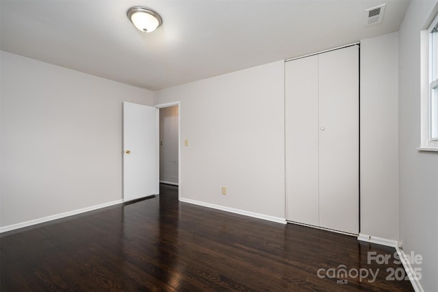 unfurnished bedroom with dark wood-type flooring and a closet