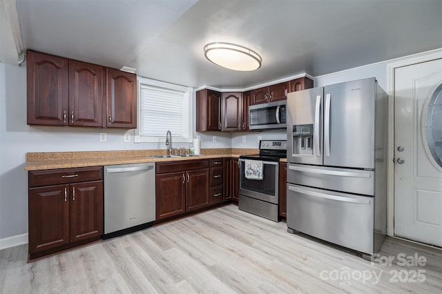 kitchen with stainless steel appliances, dark brown cabinets, sink, and light hardwood / wood-style flooring