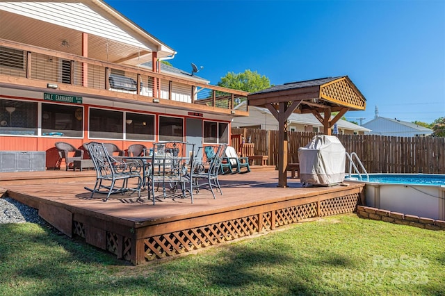 deck with a sunroom, a fenced in pool, and a lawn