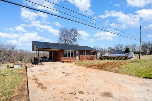 view of front of house featuring brick siding, a front yard, metal roof, a carport, and driveway