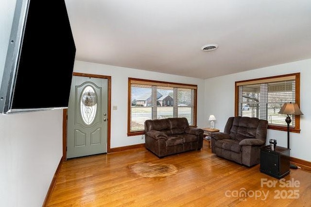 living area featuring baseboards, visible vents, and wood finished floors