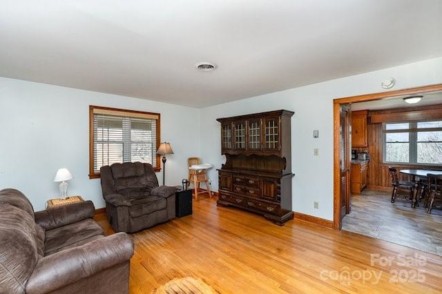 living room with baseboards, wood finished floors, visible vents, and a healthy amount of sunlight