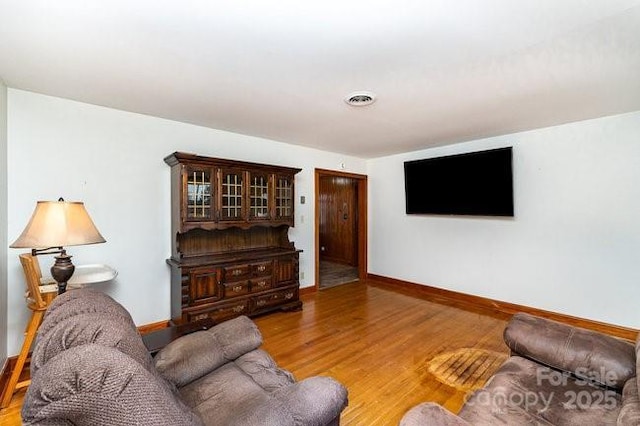 living room with wood finished floors, visible vents, and baseboards