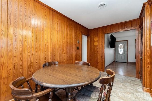 dining room featuring visible vents and wood walls