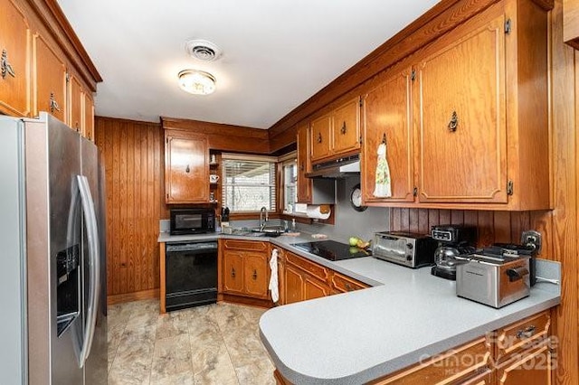 kitchen with brown cabinets, light countertops, under cabinet range hood, and black appliances