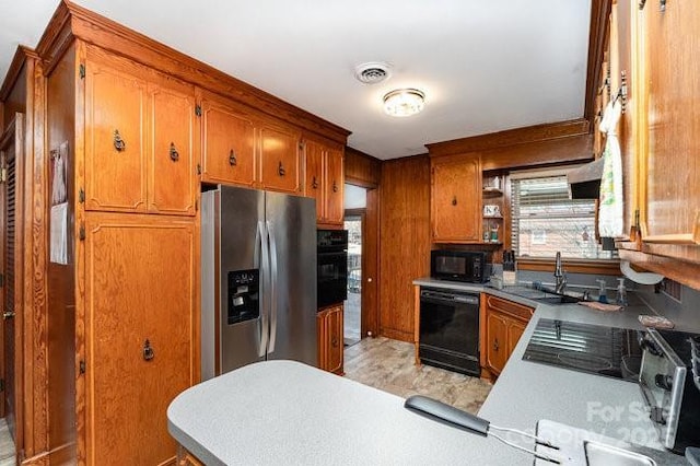 kitchen featuring brown cabinets, light countertops, visible vents, a sink, and black appliances