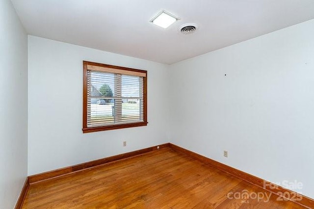 empty room with visible vents, baseboards, and wood finished floors