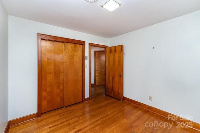 unfurnished bedroom with light wood finished floors, a closet, and baseboards