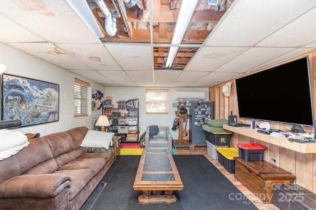 living room with an AC wall unit, a drop ceiling, and wood finished floors